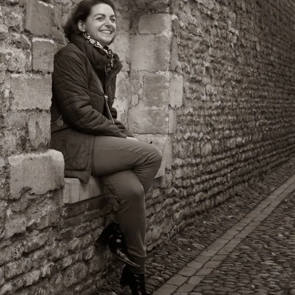 Charlotte Lestienne sitting on a stone wall in a Cambridge lane